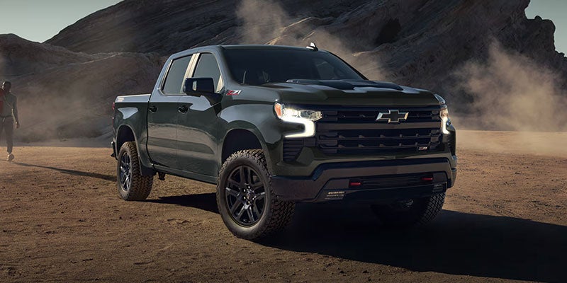 Dark green Chevrolet Silverado Z71 pickup truck parked on a rugged dirt surface in a rocky desert landscape