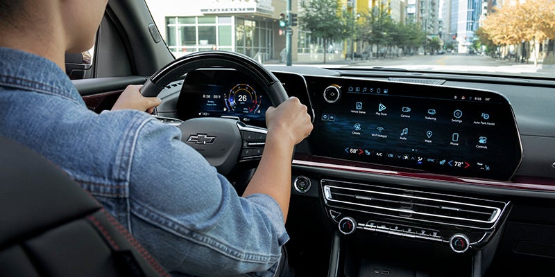 View from inside a vehicle showing a driver holding the steering wheel while traveling through an urban area