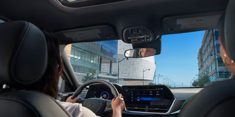 View from inside an SUV showing a person driving through an urban area, with the dashboard
